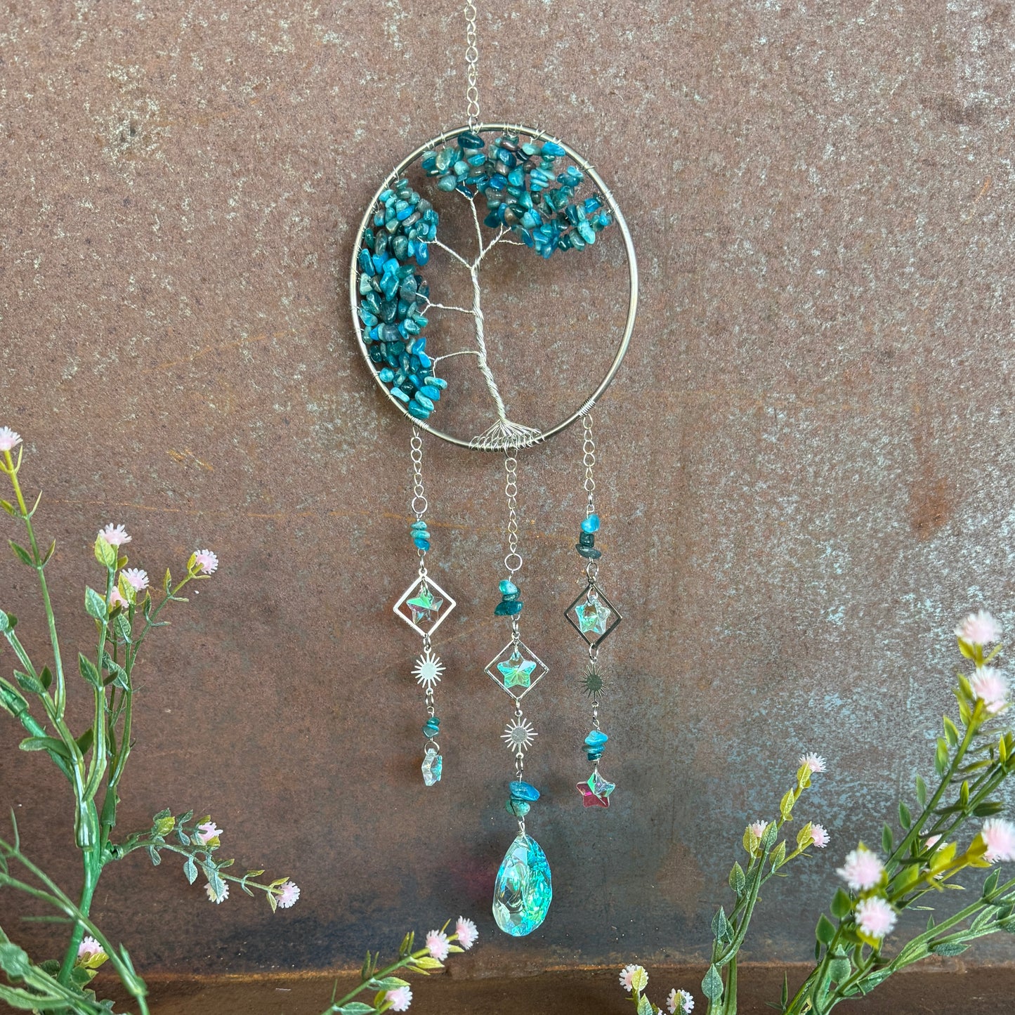Decorative Tree of Life Crystal Sun Catcher - Apatite hanging ornament with tree design and blue stones on a textured surface.
