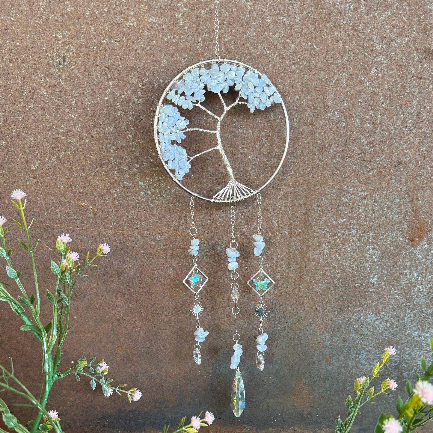Decorative Tree of Life Crystal Sun Catcher - Blue Lace Agate hanging ornament with floral design on a textured wall background