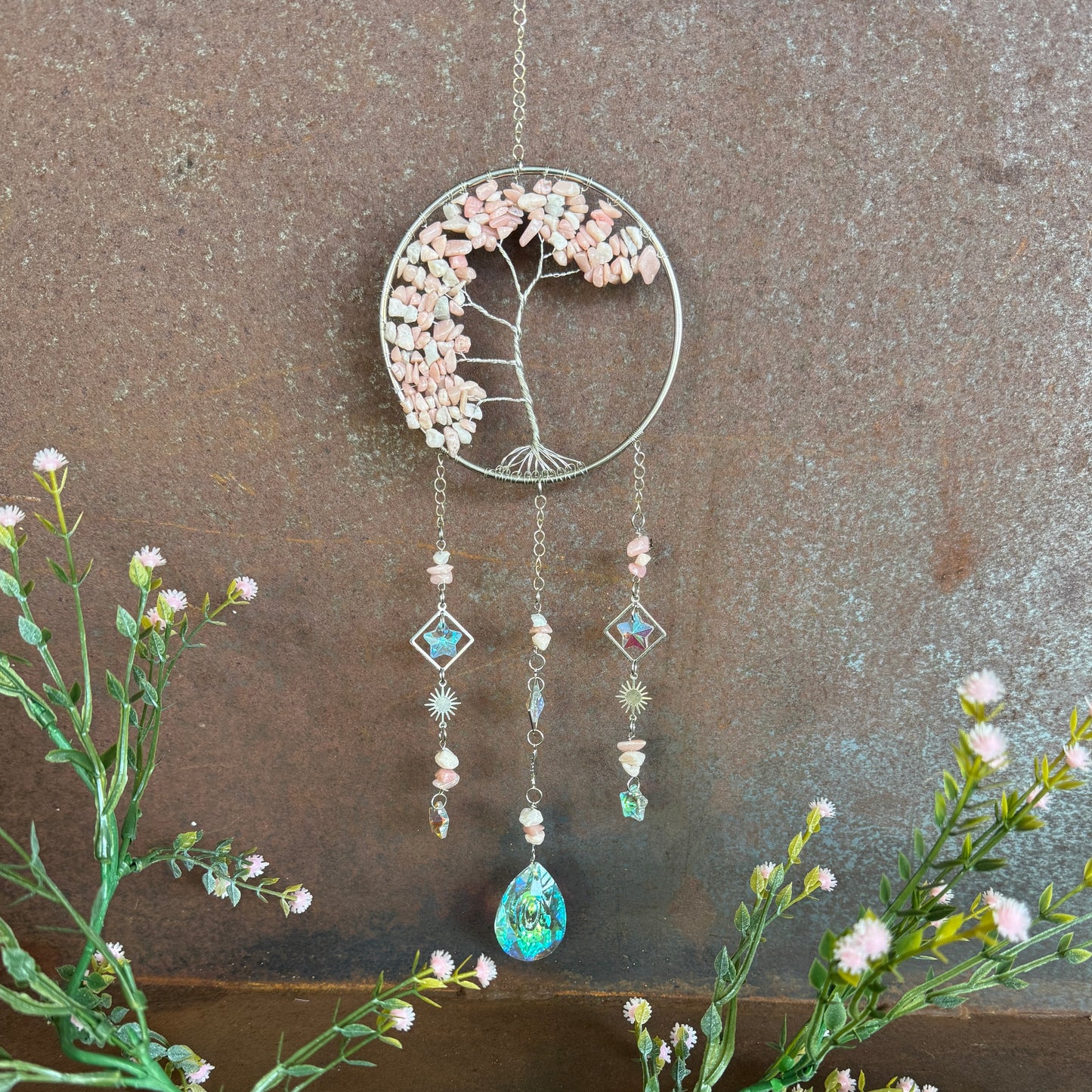 Decorative Tree of Life Crystal Sun Catcher - Pink Opal hanging ornament with floral elements and beads on a textured wall background
