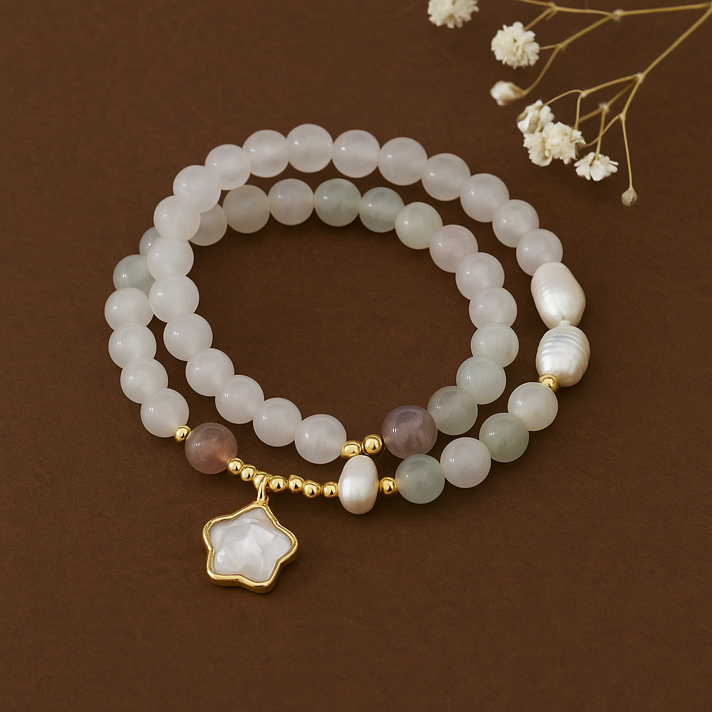 White Jade Crystal Twist Bracelet with Strawberry Quartz & Green Aventurine Two pearl bracelets with a gold charm on a brown background