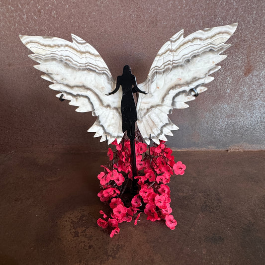 Decorative wall art with white wings and pink flowers on a brown background