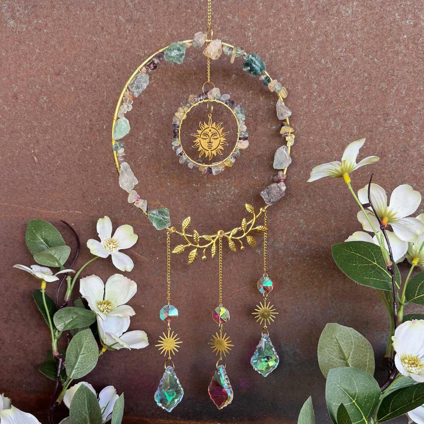 Decorative Crystal Sun Catcher - Fluorite hanging ornament with stones and sun design on a brown background with flowers.