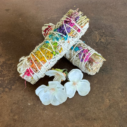 Two colorful smudge sticks with flowers on a brown surface