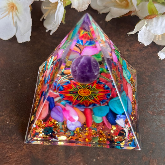 A colorful Orgonite Pyramid with seashells and an Amethyst sphere at its base, featuring a Mandala design.