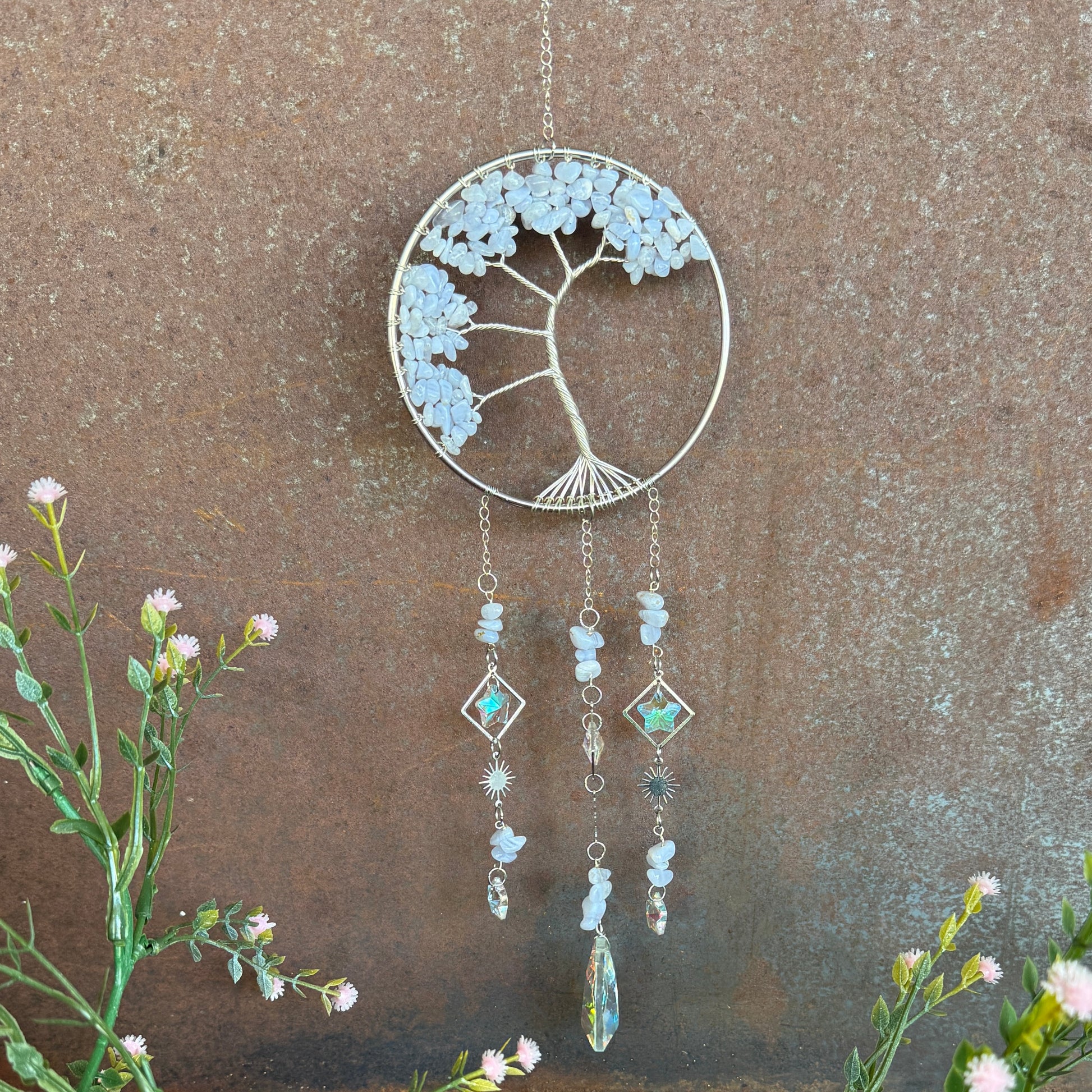 Decorative Tree of Life Crystal Sun Catcher - Blue Lace Agate hanging ornament with floral design on a textured wall background
